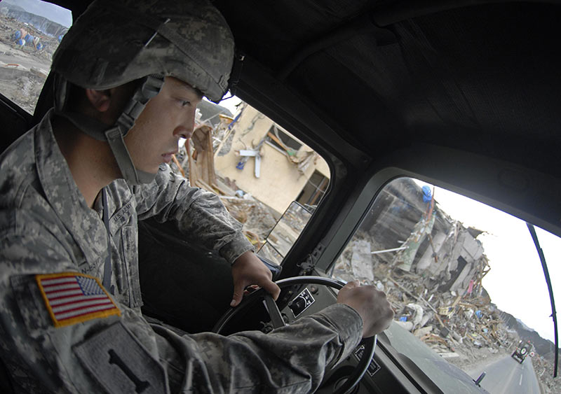 A Soldier drives a convoy truck through rubble