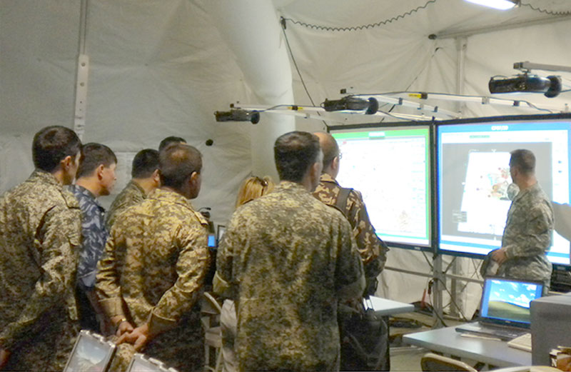 Soldiers looking at two projected computer screens