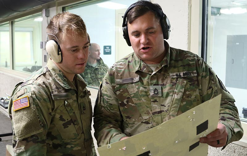 Coach of a small arms competition team gives feedback on a Soldier’s shooting performance