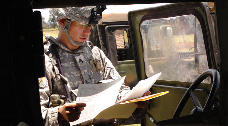 One Soldier reading paperwork in the field