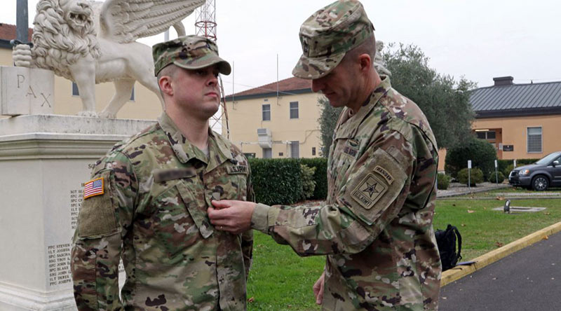 One Soldier delivering feedback on uniform appearance to another Soldier outside 