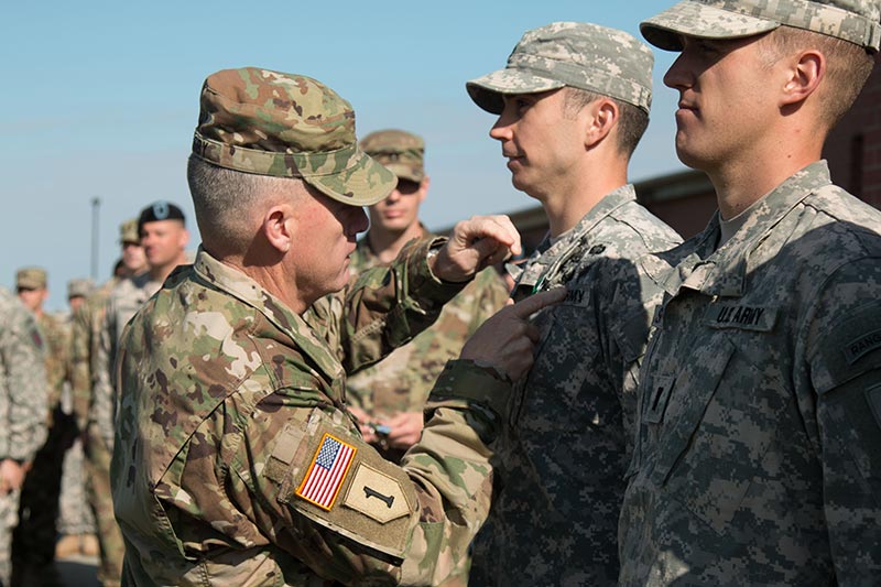 An Army leader fixing a Soldier’s uniform