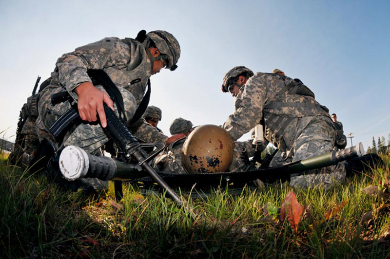 Two soldiers working on a medical patient in the field