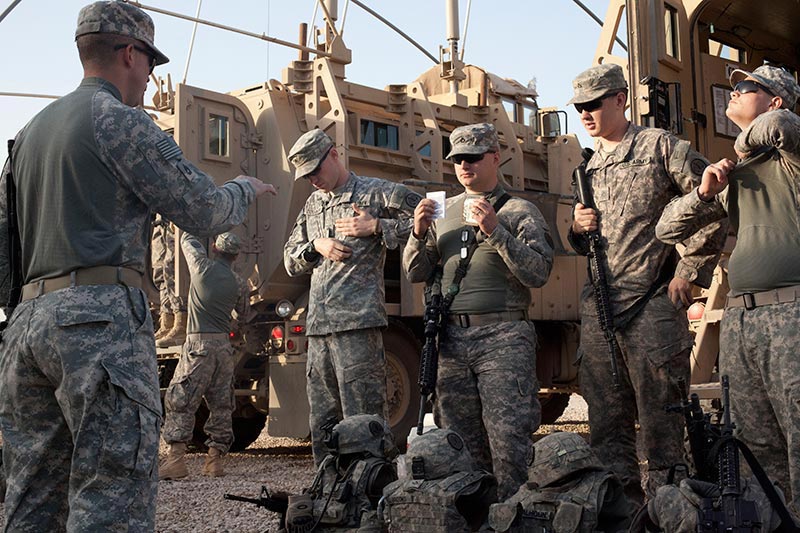 Soldiers listening to their leader while preparing for an outdoor mission