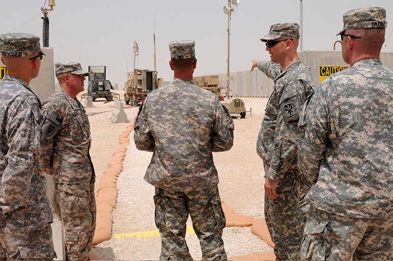 Soldier pointing at an Army vehicle while standing with other soldiers