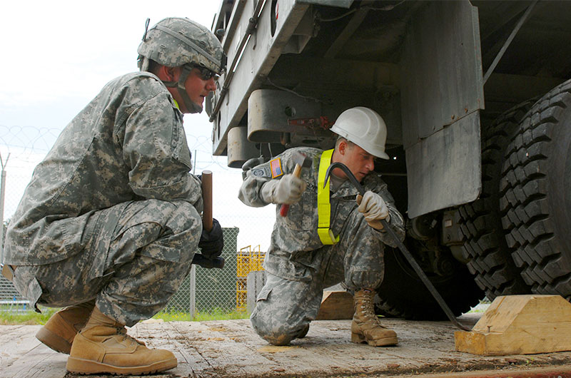 One Soldier hammering while another observess